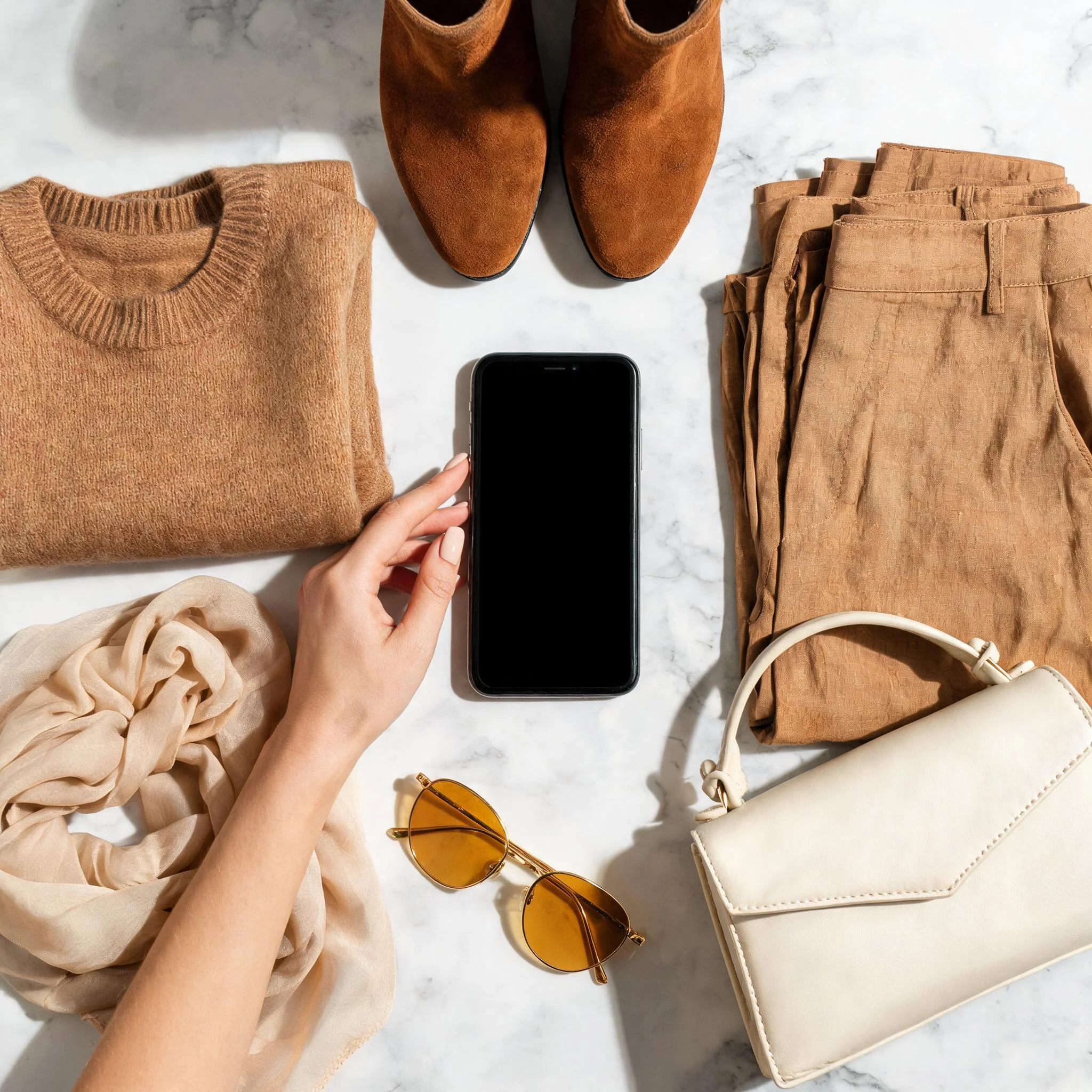 Smart packing flat lay with suitcase and neutral travel outfits radiating outward in warm beige and camel tones